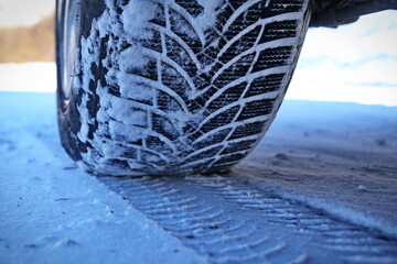Driving car with winter tire wheel on snow road