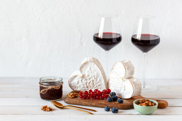 Heart shape cheese served with berries and two red wine glasses, Valentine Day