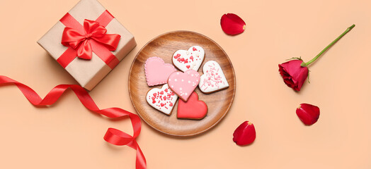 Composition with tasty heart-shaped cookies, gift and rose on beige background. Valentine's Day celebration