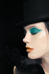 Art-deco makeup at young model with orange lips, green eyeshadows