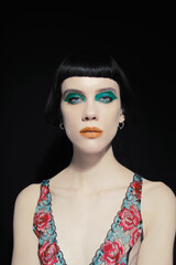 Art-deco makeup at young model with orange lips, green eyeshadows