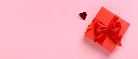 Red gift box and heart on pink background with space for text. Valentine's Day celebration
