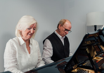 Older couple studying piano together and reading music sheet