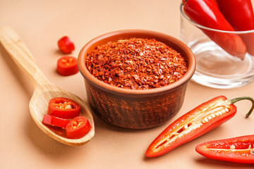 Bowl of chipotle chili flakes on color background, closeup