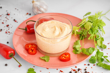 Glass of tasty chipotle sauce and spices on light background