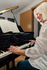 Older woman studying piano with music sheets on a grand piano