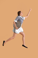 Fototapeta na wymiar Young waitress with tray jumping on beige background
