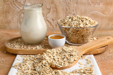 Raw oatmeal, jug of milk and honey on color background, closeup