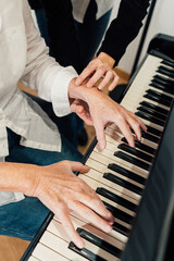 Close-up of piano teacher practicing piano lesson and finger positions with senior student