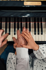 Close-up of senior piano student hands with her granddaughter playing the piano