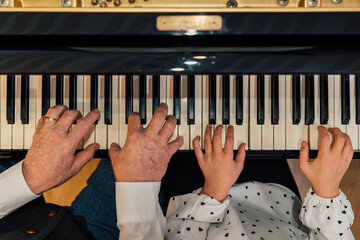 Close-up of senior piano student hands with her granddaughter playing the piano