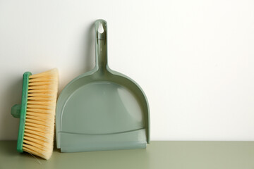 Dustpan and brush on color floor near light wall