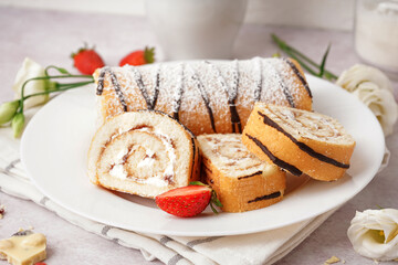 Plate with delicious sponge cake roll, fresh strawberries and floral decor on light background