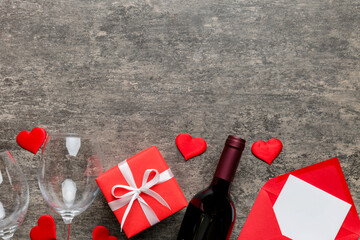 Valentine's day composition with red wine, rose flower and gift box on table. Top view, flat lay....