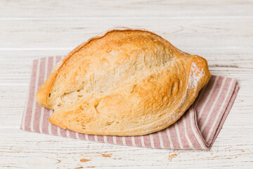 freshly baked bread with napkin on rustic table top view. Healthy white bread loaf isolated