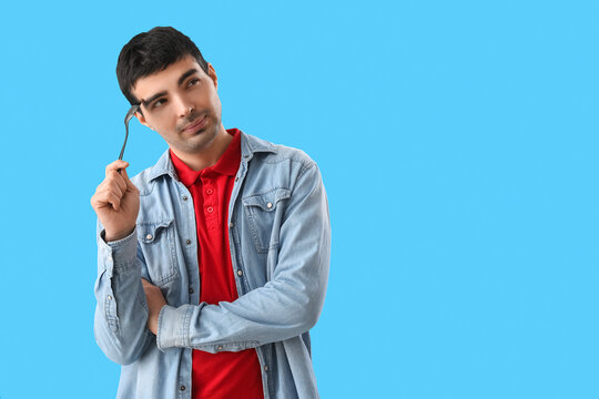 Young man with tablespoon on blue background
