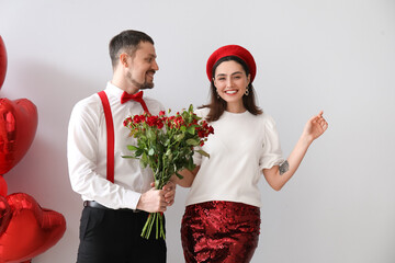 Happy couple in love with roses on grey background. Valentine's Day celebration
