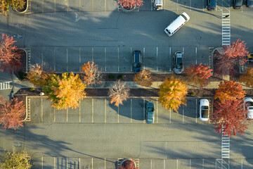 View from above of many parked cars on parking lot with lines and markings for parking places and directions. Place for vehicles in front of a strip mall center © bilanol