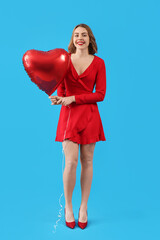Beautiful young woman with red heart-shaped balloon on blue background