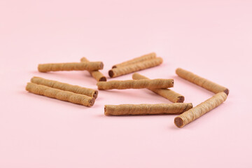 Tasty wafer rolls with boiled condensed milk on pink background