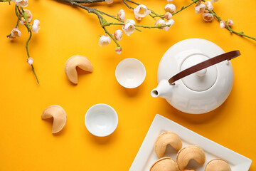 Fortune cookies, teapot, cups and sakura on yellow background. Chinese New Year celebration