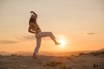 young girl on vacation dances in the sunset