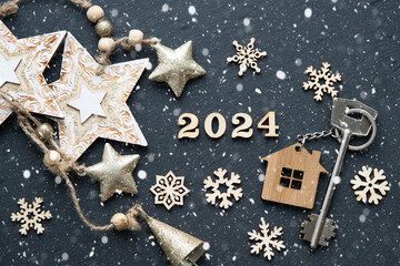 House key with keychain cottage on black background with stars, snowflakes. Happy New Year 2024-wooden letters, greeting card. Purchase, construction, relocation, mortgage