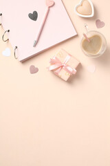 Beige elegant desk table with photo album, gift box, heart shaped candles, coffee cup, decorations. Valentines Day concept.