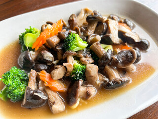 stir fried mushroom with broccoli carrot vegetable, shiitake mushrooms with oyster sauce cooking food on white plate, shiitake mushroom cooked by frying rapidly over a heat