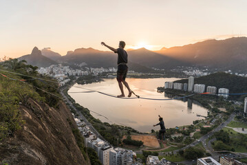 Manâ€ slackliningâ€ at sunset, Morroâ€ doâ€ Cantagalo, Rioâ€ deâ€ Janeiro, Brazil