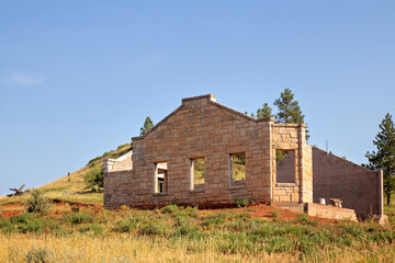 A brick store with partial walls in the process of being built in a sunny summer rural landscape