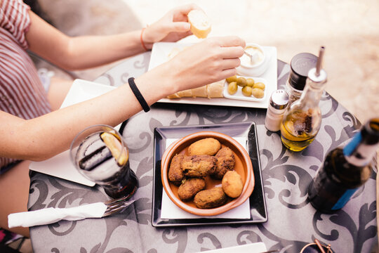 Woman eating typical Spanish food. Croquettes olives and garlic sauce