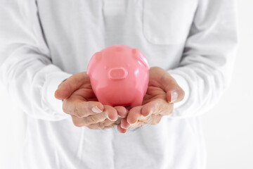 豚の貯金箱を持っている男性の手