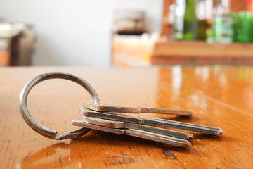 Set of keys on varnished wooden table and blurred background.