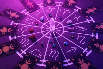 Natural stones for zodiac signs, tarot cards and drawn astrology chart on purple background. Color tone effect