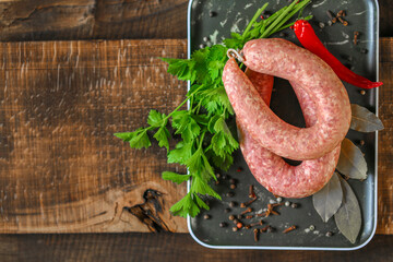  sausage rings.Raw homemade sausage rings, fresh parsley, red chili peppers in a black dish on a...