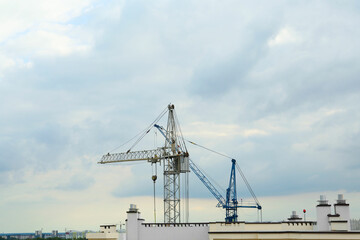 Fototapeta na wymiar Construction site with tower cranes near building under cloudy sky