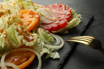 Delicious salad with Chinese cabbage, tomatoes and onion served on black table, closeup