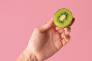 Woman holding delicious fresh kiwi on pink background, closeup