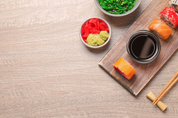 Flat lay composition with delicious sushi rolls on wooden table. Space for text