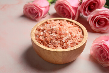 Fototapeta na wymiar Aromatic sea salt and beautiful roses on pink marble table, closeup