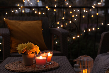Beautiful view of garden furniture with pillow, soft blanket and burning candles at balcony