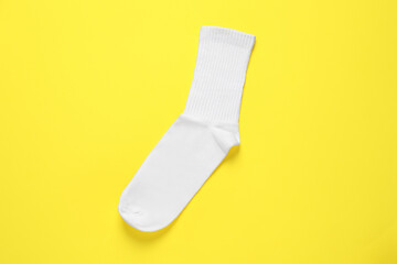 One white sock on yellow background, top view