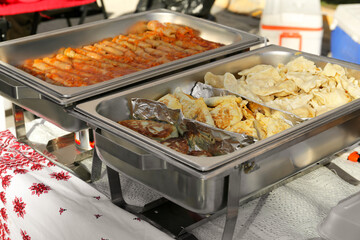 Delicious stuffed cabbage, dumplings and patties in warmers on table outdoors. Volunteer food...