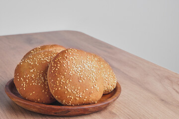 Fresh buns with sesame seeds on wooden table. Space for text