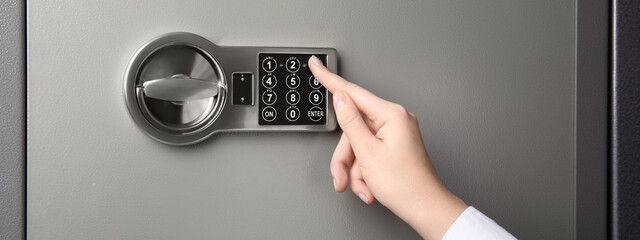 Woman opening steel safe with electronic lock, closeup. Banner design