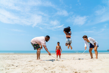 Happy African family on summer holiday vacation. Father, mother and child playing jump rope...