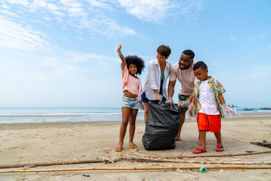 Group of Happy African family on summer holiday vacation. Parents teaching children kid picking up plastic bottle and garbage on the beach. Environment protection volunteer and waste pollution concept