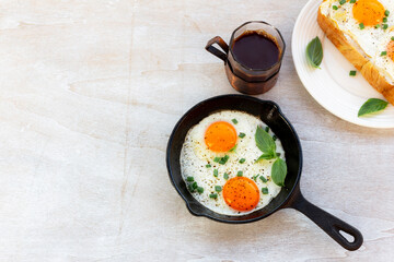 Healthy breakfast food fried egg in skillet pan and coffee on white wood table.