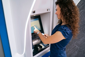 Young attractive curly hair woman smiling while using ATM